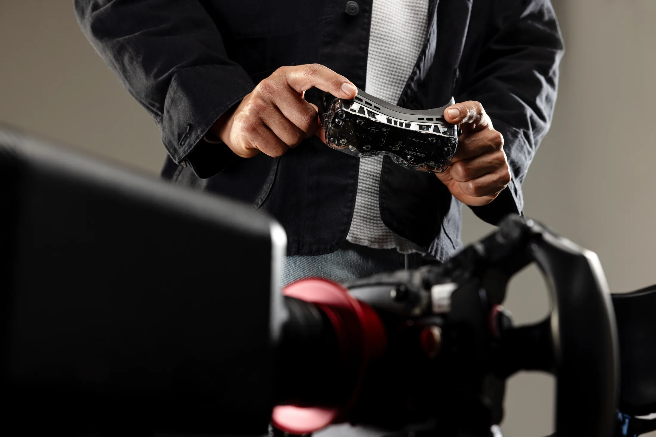 Driver holding a Beyond 2 headset at a racing simulator